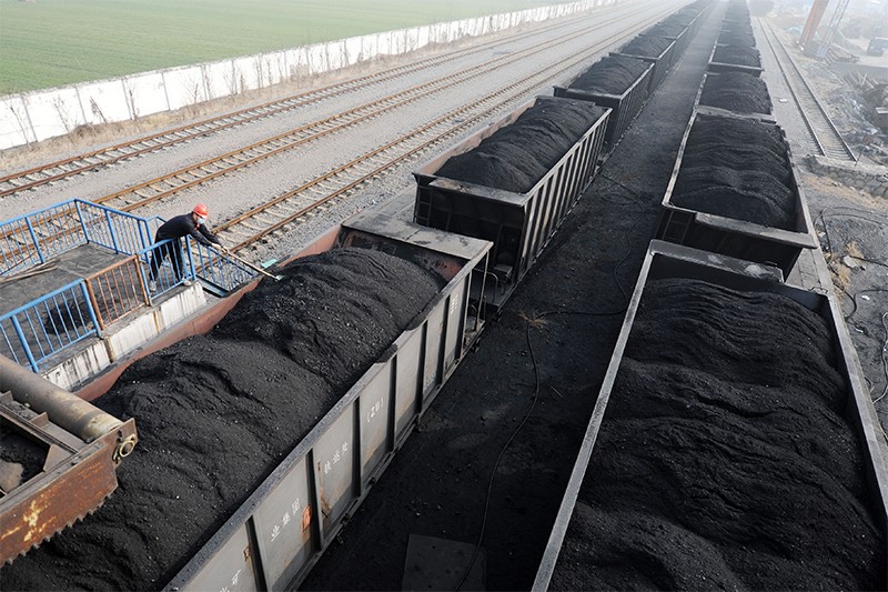 A worker shovels up coal on a freight train at a state-run coal mine in Huaibei, Anhui province, China