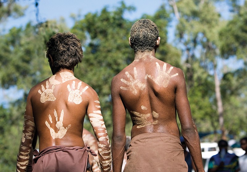 Two Aboriginal people display handprint decorations on their backs