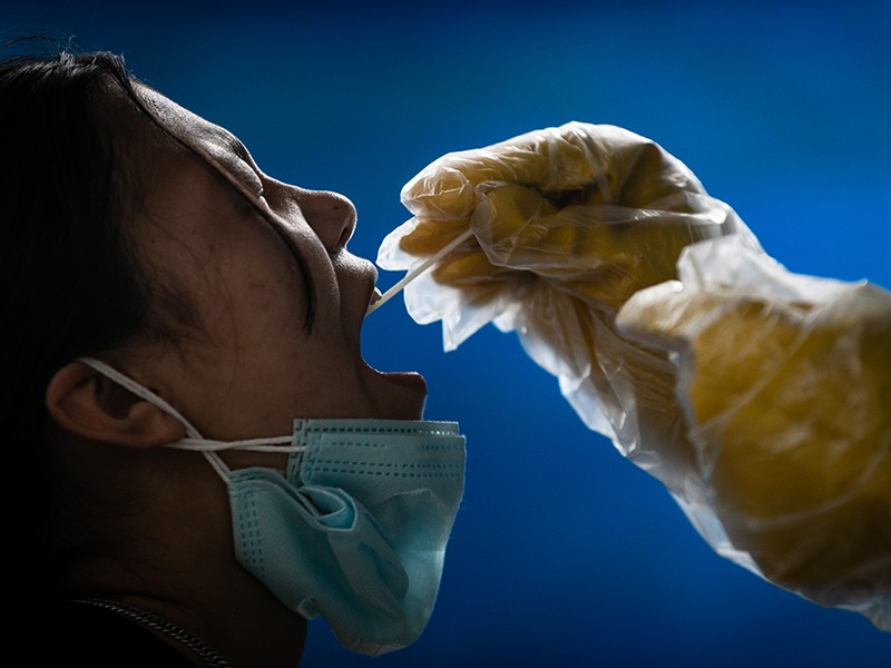 A health worker collects the throat swab from a girl for Polymerase chain reaction (PCR) test in Nepal.