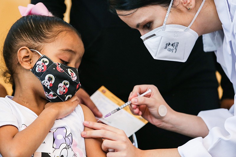 A six-year-old girl receives a dose of Pfizer vaccine by a heath-care worker in in Sao Paulo, Brazil.