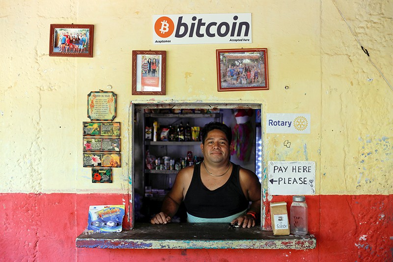 The owner of a small store stands at the window of his business where he accepts Bitcoins at El Zonte Beach in El Salvador.