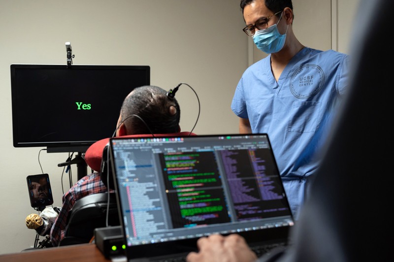 The word 'Yes' appears on a screen as Eddie Chang and a colleague help a paralysed man speak through an implant in his brain