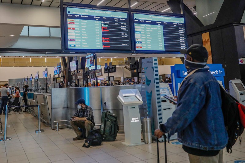 A passenger looks at an electronic flight notice board displaying cancelled flights at an airport in Johannesburg November 2021