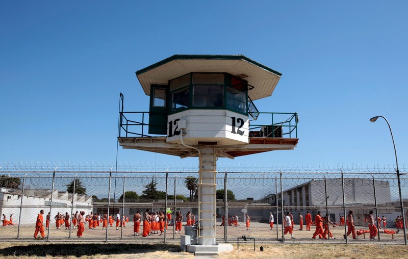 Des personnes incarcérées se promènent dans une cour d'exercice à l'extérieur de la prison d'État de la California Institution for Men.