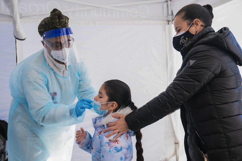 A health technician administers a nasal swab to a child to test for COVID-19