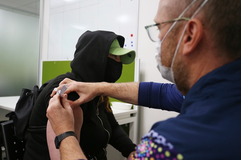 A hooded and masked woman receives a Pfizer vaccination.