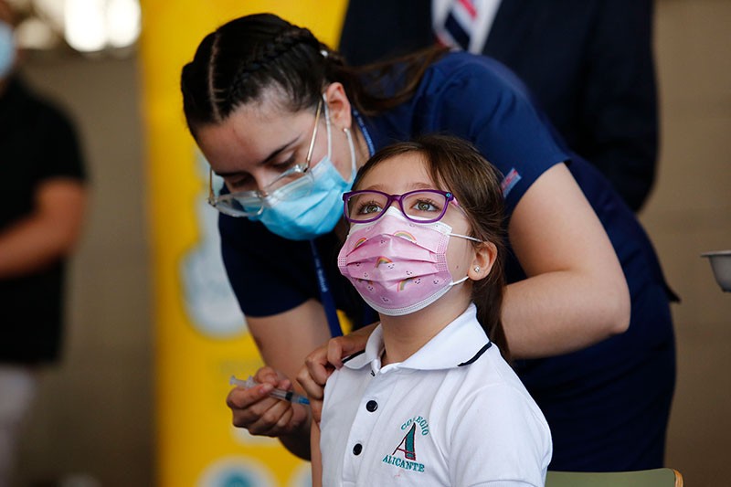 A health worker administers the first dose of Sinovac vaccine to a child in Santiago, Chile.