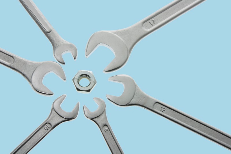 Photo illustration of a six differently sized spanners surrounding a hex nut
