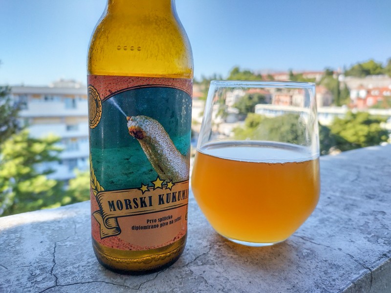 A bottle of beer labelled 'Morski kukumar' with a picture of a sea cucumber next to a glass of beer