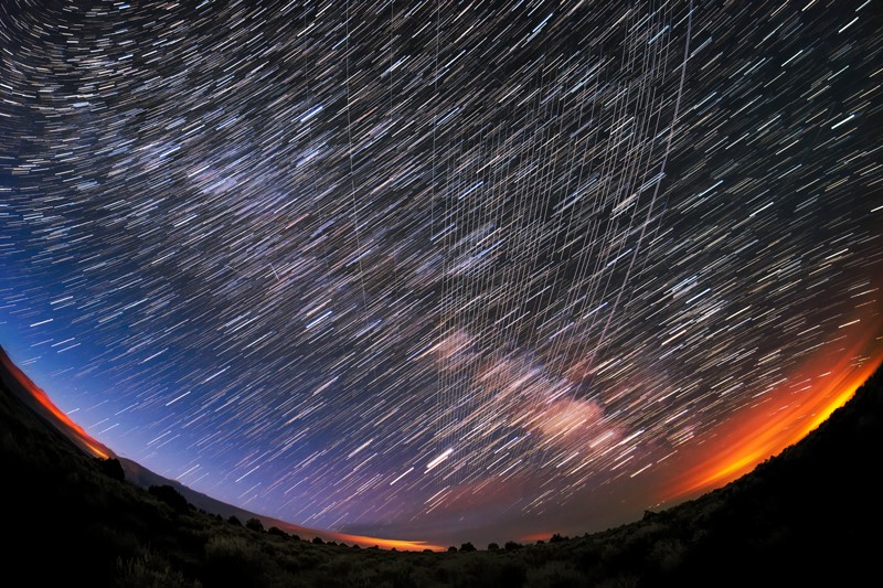 A super wide angle view of Starlink Satellites streaking across a night sky