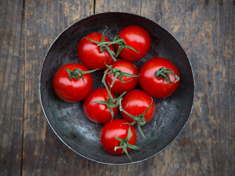Dubuo su vyšniniais pomidorais ant medinio stalo, vaizdas iš viršaus.