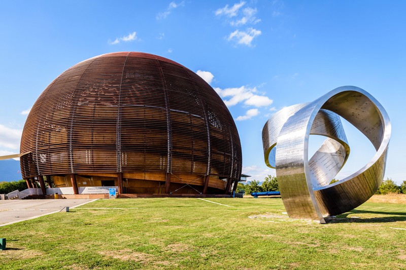 Outside view of the steel ribbon and the Globe of Science and Innovation at CERN on a sunny day.