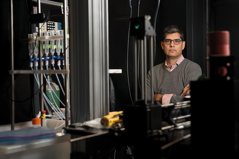 Sandeep Robert Datta stands by a machine with tubes and bottles, which will send smells to mice.