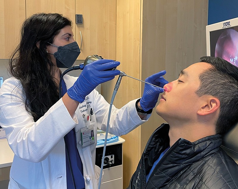Zara Patel inserts a probe into male patient’s nostril, guided by a screen showing his nasal interior.