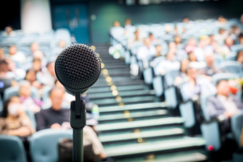 View of a microphone in front of an auditorium of seated people
