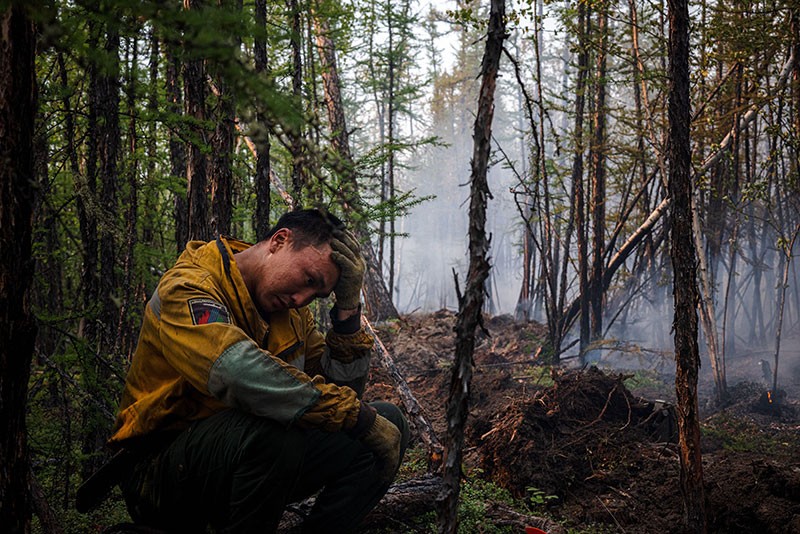 A member of the Aerial Forest Protection Service monitors a backfire at the edge of the village of Byas-Kyuel, Russia