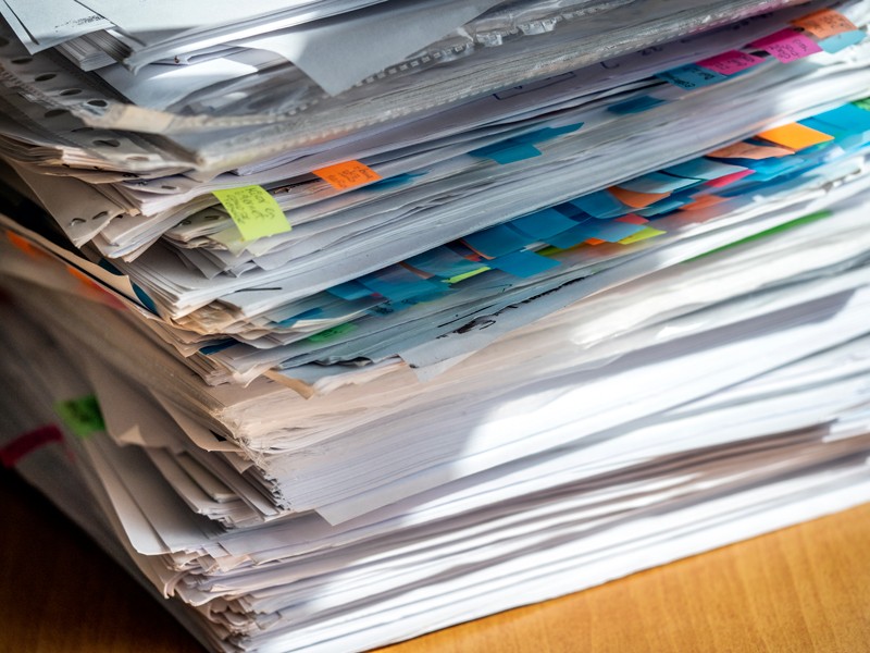 A close up of a stack of papers and documents with multi-coloured sticky tabs