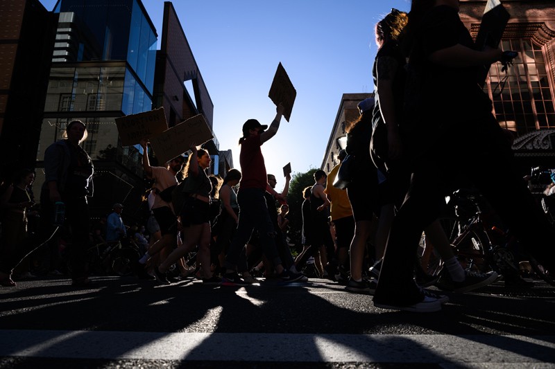 Low-angle silhouette view of people marching during a protest.