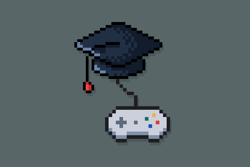 An 8 bit style gaming controller attached to a graduation cap on a dark grey background