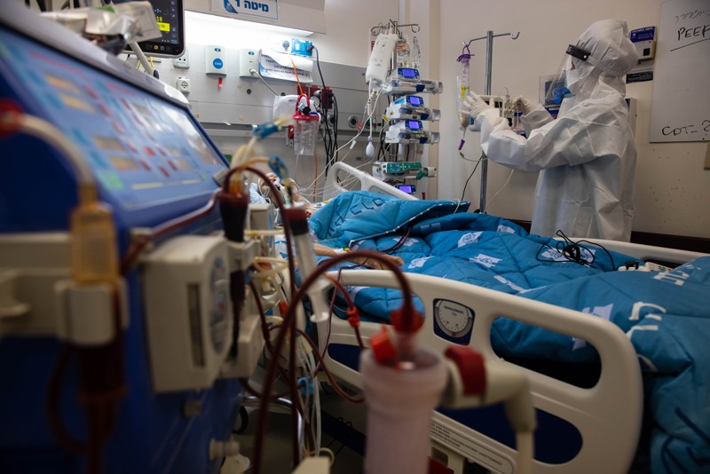 A patient on an ECMO machine lies in a bed in hospital