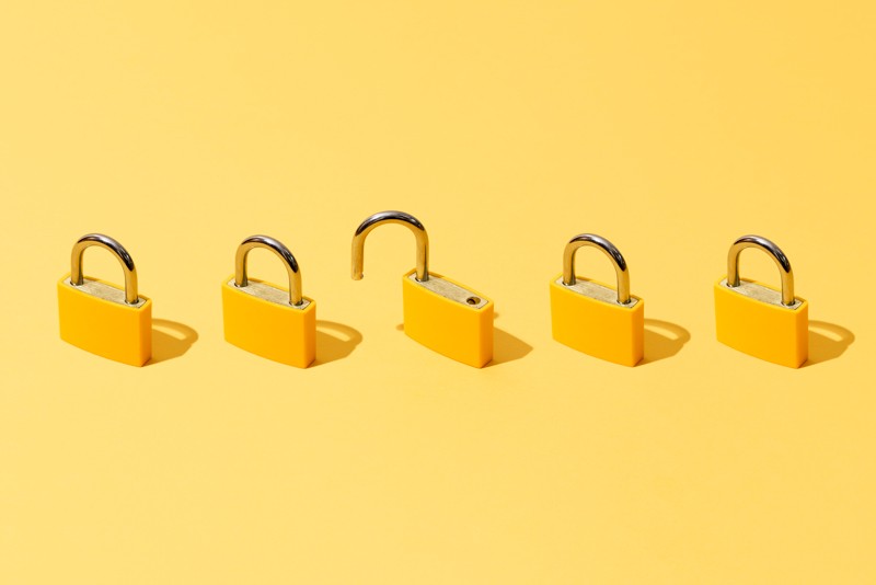Five yellow padlocks on a pale yellow background, the middle one is unlocked