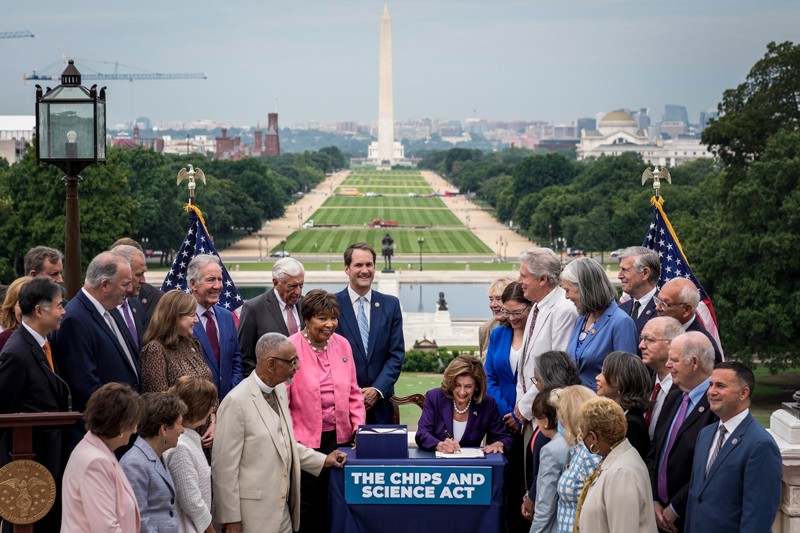 Nancy Pelosi, surrounded by House Democrats, signs the CHIPS For America Act outside the U.S. Capitol