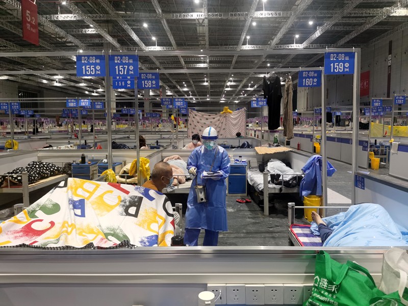 A nurse wearing PPE talks to a patient in a temporary hospital for Covid-positive people