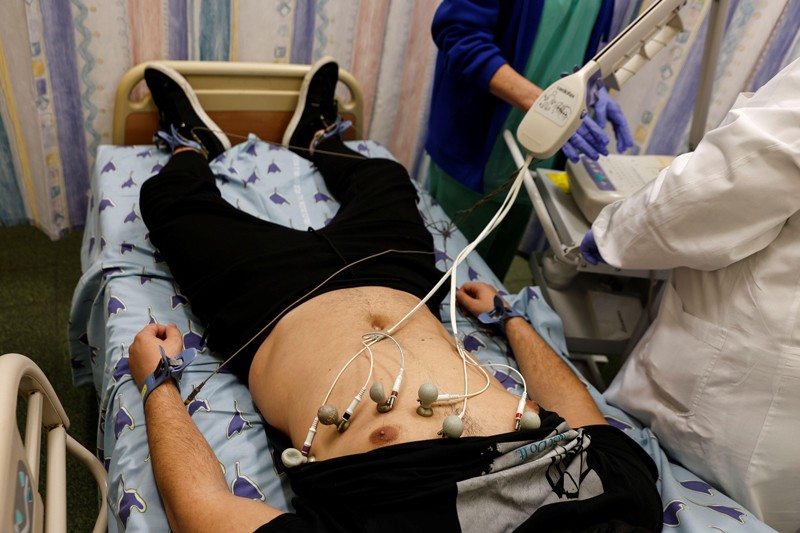 A patient lying on a hospital bed with sensors attached to his chest at a long COVID clinic