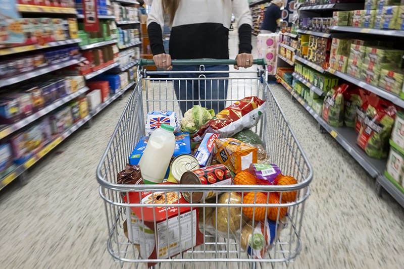 Uma pessoa com um carrinho de compras cheio de mantimentos em um corredor de supermercado em 22 de maio de 2022 em Cardiff, País de Gales.