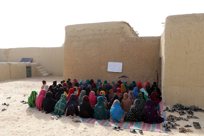 A group of Afghan girls sit with their backs to the camera during a class held by volunteers