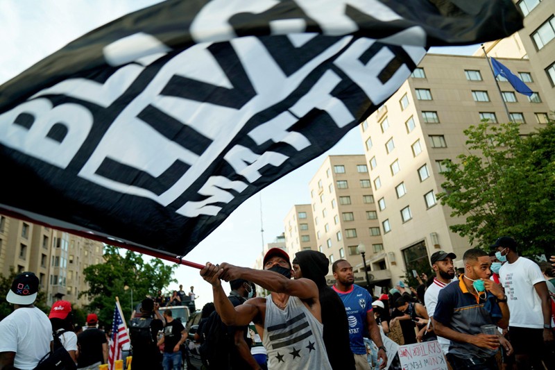 A man waves a flag with the Black Lives Matter logo printed on it at a demonstration in Washington D.C.