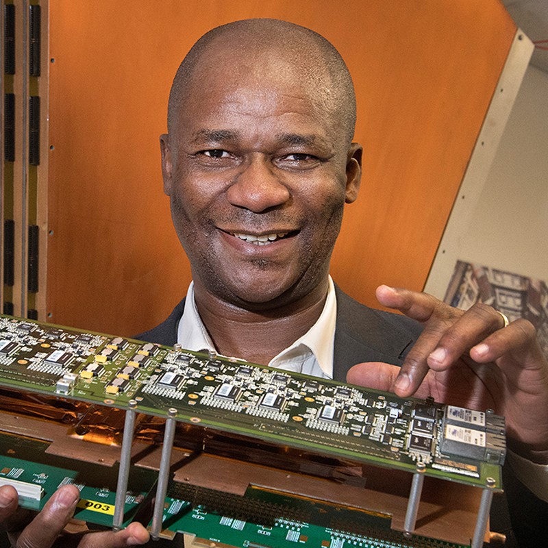 Physicist Kétévi Assamagan shows sample components from the muon spectrometer for the ATLAS detector.