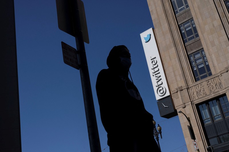 A silhouetted man stands in front of the Twitter headquarters in downtown San Francisco