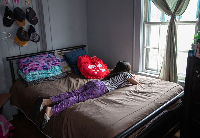 A Honduran asylum seeker, 8, looks from her bedroom window during self-quarantine for possible COVID-19 in New York.