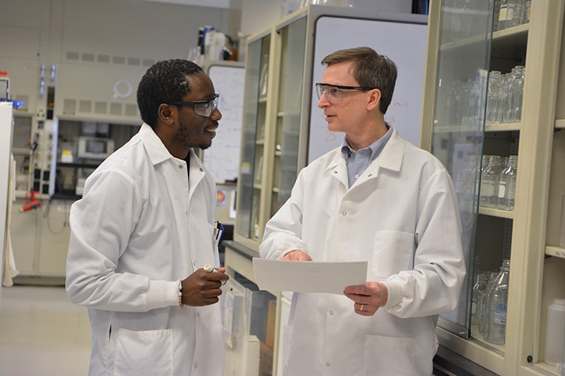 Craig Crews talks to postdoc Momar Toure in a laboratory