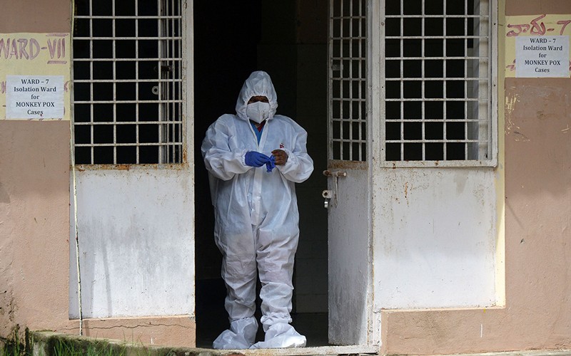A nurse in protective gear stands at the entrance to an isolation ward for monkeypox patients.