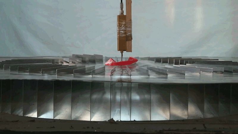 Short looping clip of a red toy boat bobbing on waves in the centre of the 86cm prototype of the wave concentrator device