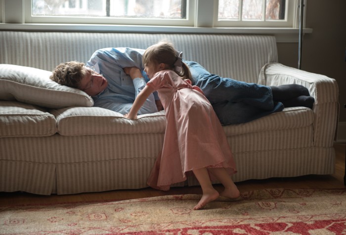 A young girl waking her dad up from his nap