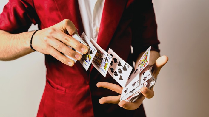 Hands of magician doing tricks with a deck of cards.