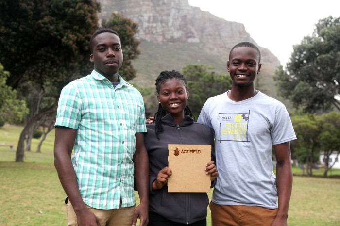 Elikplim Ampofo, Mary Twumasi and Victor Kumbo pose for a photo holding a square piece of wood branded with the word 'Actifield'