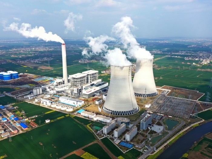 Smoke rises from two huge chimneys at a power plant.