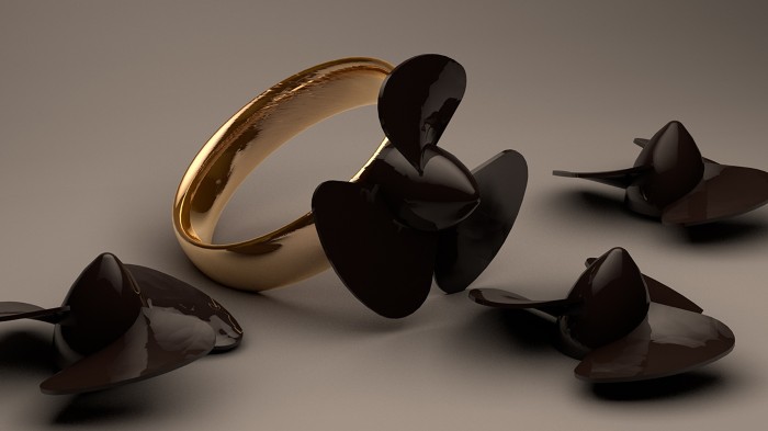 A gold wedding ring with a black plastic propeller on it sits amid other broken propellers