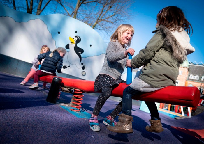 Children play on playground equipment on a sunny day in Copenhagen