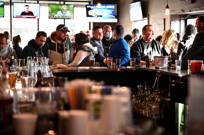Customers drink and ear in a busy bar in Minnesota while sports are shown on screens