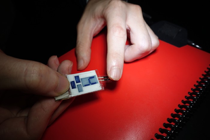 Close up of a finger tip being held against a vitamin C sensor with an electrochromic display reading '4'