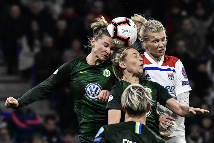 Three players all compete for a header, almost making contact with the ball, at a UEFA Women's Champions League match 2019
