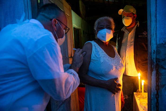 Raimunda Nonata, 70, is inoculated with the Sinovac Biotech's CoronaVac vaccine inside her house in Brazil.