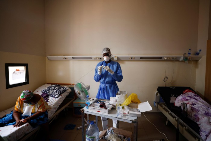A nurse wearing PPE prepares a treatment for a COVID-19 patient in a hospital in Dakar