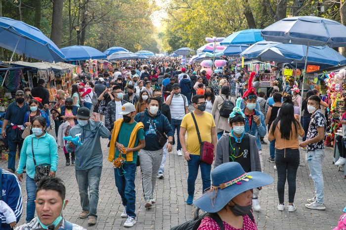 Street scene in Mexico City with umbrellas at vendor stalls and many people walking around.