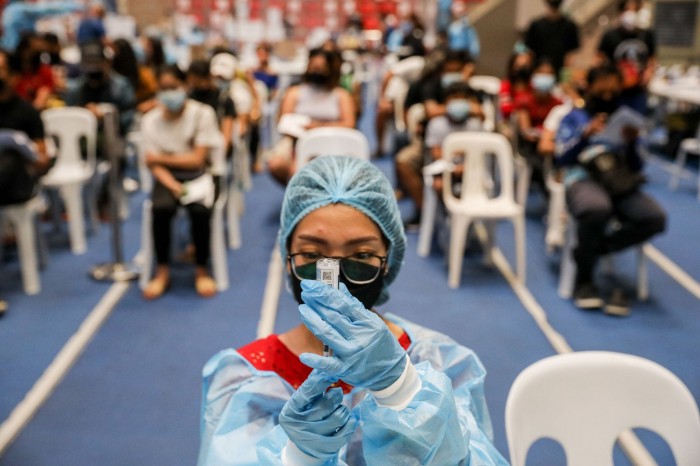 A health worker transfers a dose of Moderna's COVID-19 vaccine into a syringe at a vaccination drive in a stadium in Manila